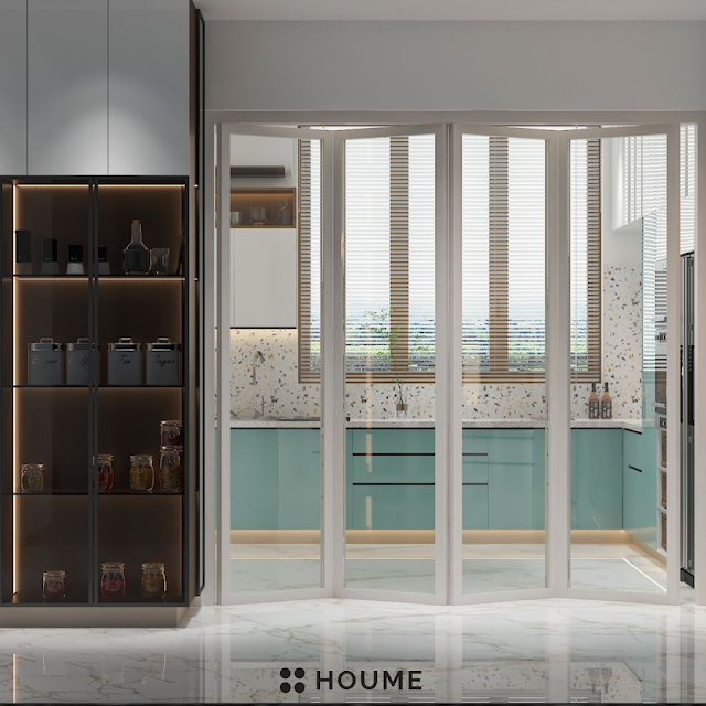 Modern kitchen with open wood shelves, warm stained butcher block breakfast bar with black metal legs and stools, stainless steel sink with a gooseneck faucet, and a window with a black frame overlooking a green backyard. Text overlay: Houme India - Kitchen Design Ideas. C
