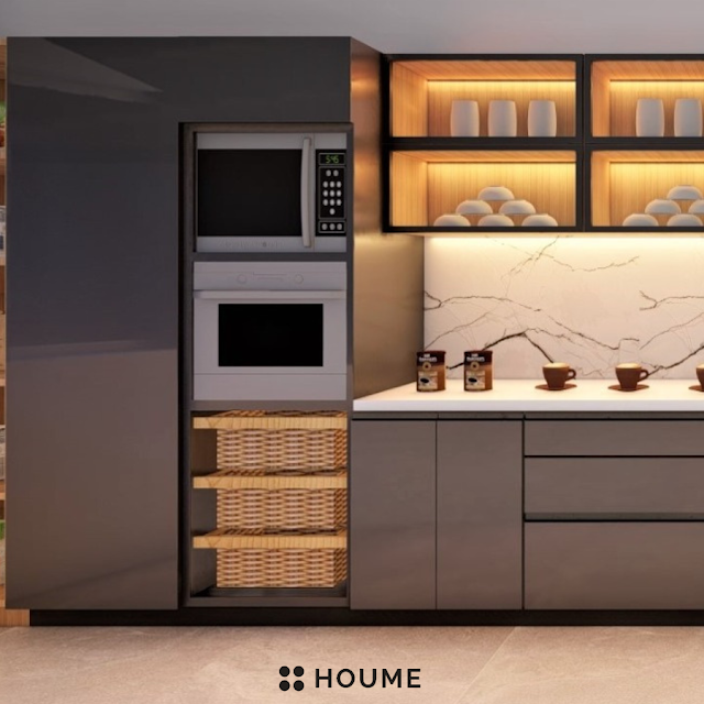 Modern kitchen with black stainless steel stovetop, oven, and vent hood, light wood cabinets, and a white quartz countertop. A ceiling fan with woven blades hangs from the ceiling. Text overlay: Houme India - Kitchen Design Ideas. C