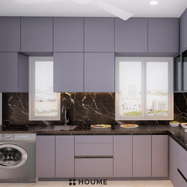Luxurious kitchen featuring a large white marble island with waterfall edges, brass fixtures, and dark wood cabinetry. Text overlay: Houme India - Kitchen Design Ideas.C