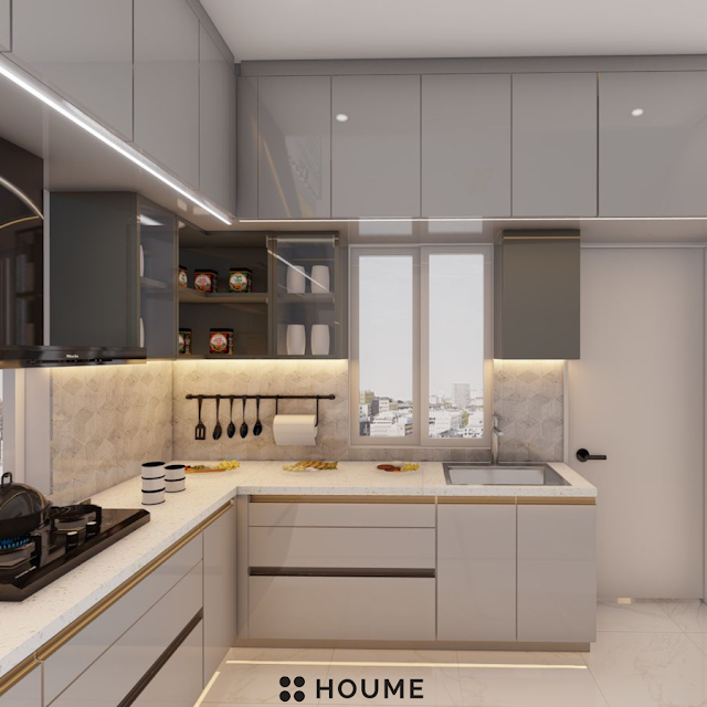Modern kitchen with a sleek black vent hood over a stainless steel stovetop and built-in oven, light wood cabinets, and white quartz countertops. Text overlay: Houme India - Kitchen Design Ideas. B