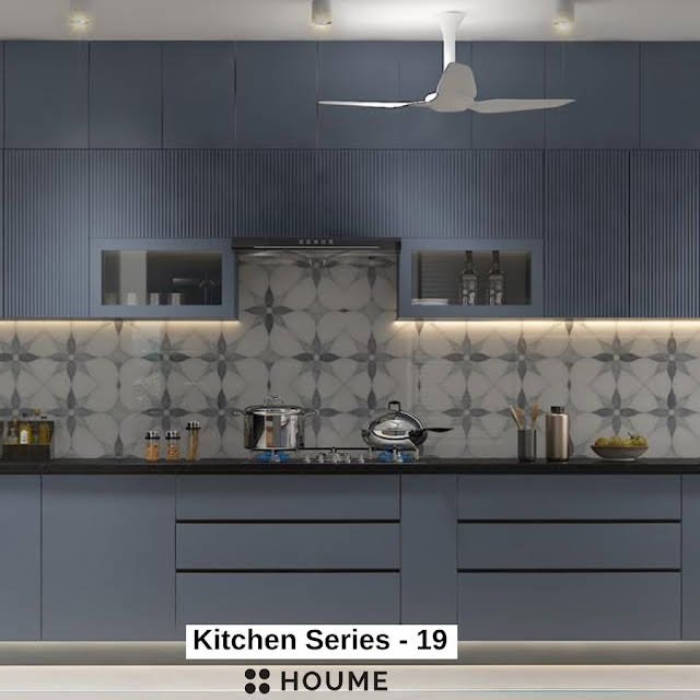 Modern kitchen with a large farmhouse sink and a window with a black frame, overlooking a green backyard. Text overlay: Houme India - Kitchen Design Ideas.