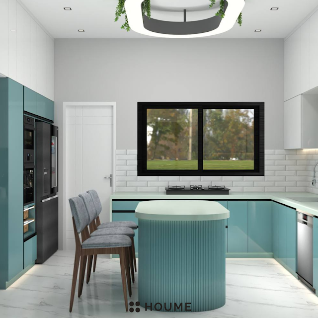 Kitchen with a stainless steel stove and a black pot simmering on the burner. A window with a black metal frame is above the stove, revealing a green backyard. A white patterned tile backsplash adds a decorative touch behind the stove. Text overlay: Houme India - Kitchen Design Ideas. D