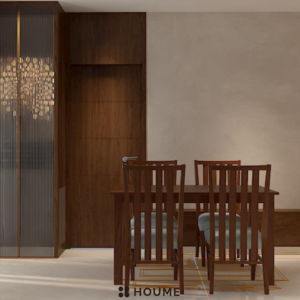 Living room with a modern gray couch, two brown accent chairs, and a round wooden coffee table with black metal legs. A woven jute rug sits underneath the furniture, and a large plant adds a touch of nature to the space. Text overlay: Houme India - Interior Design Ideas. D
