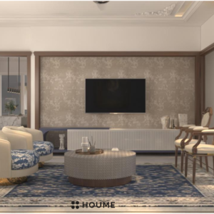 Living room with a modern abstract painting in shades of blue, green, and brown hanging on a white wall. A gray fabric sofa sits across from the painting, with a round wooden coffee table and a woven jute rug in the center of the space. Text overlay: Houme India - Interior Design Ideas. D