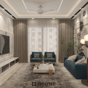 Modern living room with a large flat screen TV mounted on a white wall, a gray fabric sofa with a wooden coffee table and a woven jute rug. Text overlay: Houme India - Interior Design Ideas. B