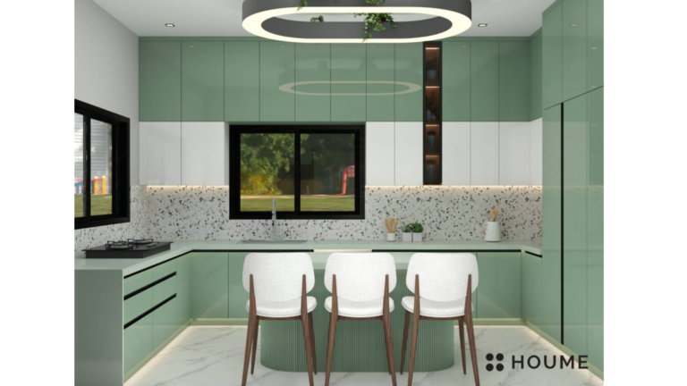 Kitchen interior featuring green cabinets with chrome hardware and black countertops. A black refrigerator and oven are visible in the background. Text overlay: Houme India - Interior Design Ideas. D