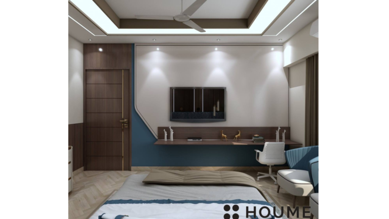 Bedroom interior featuring a king-size bed with a dark wood headboard and white bedding. A white nightstand with a lamp sits on the left side of the bed. There is a window with white blinds on the left wall. Text overlay: Houme India - Interior Design Ideas. D