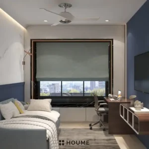 Cozy guest bedroom interior featuring a blue daybed with a white comforter and pillows. A nightstand with a lamp sits beside the daybed. A ceiling fan hangs from the ceiling. Text overlay: Houme India - Interior Design Ideas. C