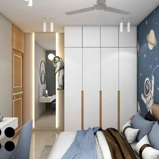 Mid-century modern bedroom interior featuring a platform bed with a walnut wood frame, a woven cream blanket and pillows, and a round wooden nightstand with a drawer. A woven jute rug covers the floor. A ceiling fan with woven blades hangs from the ceiling. The wall behind the bed is painted a light blue color. Text overlay: Houme India - Interior Design Ideas. B