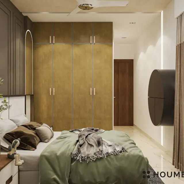 Mid-century modern bedroom interior with a low profile platform bed in walnut wood with a woven cream blanket and pillows. A round wooden nightstand with a single drawer sits beside the bed. A woven jute rug in a light natural color covers the floor. Text overlay: Houme India - Interior Design Ideas. D
