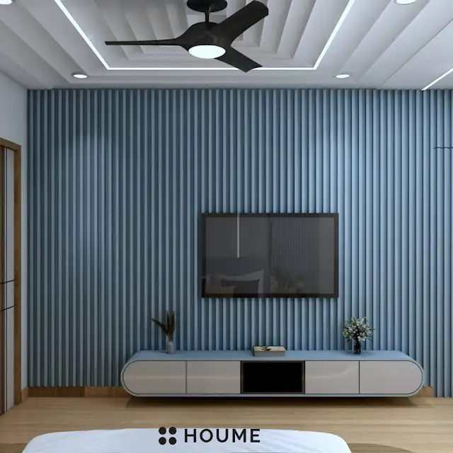 Bedroom featuring a mid-century modern bed with a tufted headboard and tapered wooden legs. A round wooden nightstand with a drawer sits beside the bed. A woven jute rug in a light natural color is on the floor. Text overlay: Houme India - Interior Design Ideas. D