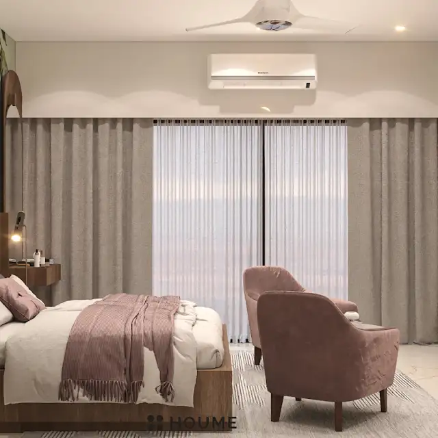Bedroom featuring a mid-century modern platform bed with a walnut wood frame and a woven cream blanket and pillows. A round wooden nightstand with a drawer sits beside the bed. A woven jute rug in a light natural color covers the floor. A ceiling fan with woven blades hangs from the ceiling. Text overlay: Houme India - Interior Design Ideas. B