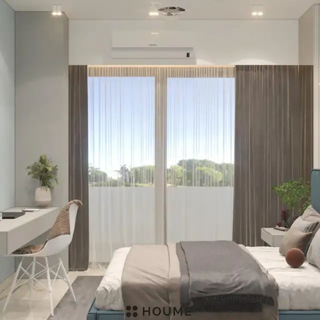 Mid-century modern bedroom interior featuring a platform bed with a walnut wood frame and a woven cream blanket and pillows. A round wooden nightstand with a drawer sits beside the bed. A woven jute rug in a light natural color covers the floor. A ceiling fan with woven blades hangs from the ceiling. Text overlay: Houme India - Interior Design Ideas. C