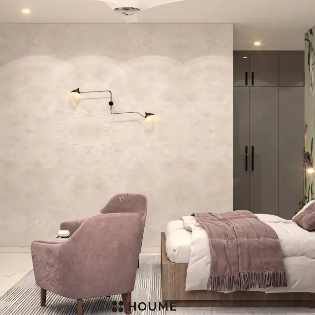Bedroom featuring a mid-century modern platform bed with a walnut wood frame and a woven cream blanket and pillows. A round wooden nightstand with a drawer sits beside the bed. A woven jute rug in a light natural color covers the floor. A ceiling fan with woven blades hangs from the ceiling. Text overlay: Houme India - Interior Design Ideas. D