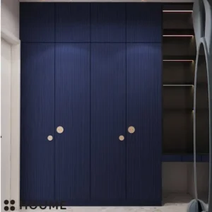 Walk-in closet interior featuring a whimsical rabbit-shaped mirror on the back wall. Wood shelves line the walls on either side of the mirror, and wood drawers with chrome knobs are installed below the shelves on one side. Text overlay: Houme India - Interior Design Ideas. B