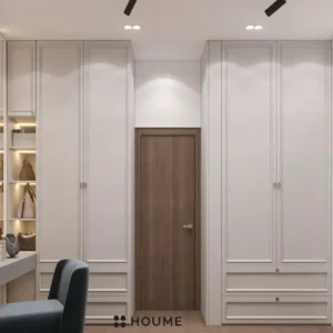 Walk-in closet interior featuring a vanity with a white countertop, a rectangular mirror with a chrome frame above the countertop, and open wood shelves lining the walls. Text overlay: Houme India - Interior Design Ideas. B