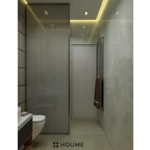 Simple, clean bathroom interior featuring a white toilet, pedestal sink with a chrome faucet, and a rectangular mirror with a chrome frame above the sink. The walls are a light beige color and there is a window with frosted glass on the right wall. Text overlay: Houme India - Interior Design Ideas. C
