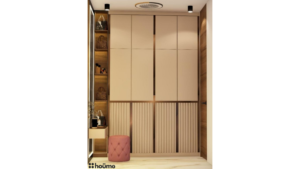 Walk-in closet featuring floor-to-ceiling wardrobes, a vanity table with a cushioned stool, and illuminated mirrors. The space is designed with a neutral color palette and warm lighting. B