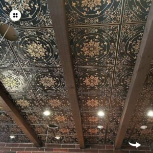 An elegant living room with a black and gold ceiling featuring decorative tiles.