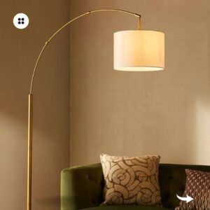 A gold arc floor lamp illuminates a green velvet sofa in a modern living room.