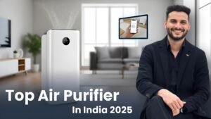 A sleek, modern white air purifier with a digital display emitting clean air particles, positioned in a contemporary living room. A confident man (Sourabh) in a black suit smiles and gestures towards the purifier. An inset image shows a hand controlling the air purifier via a smartphone app. The title "Top Air Purifier In India 2025" is prominently displayed at the bottom, against a blurred background of a stylish home interior.