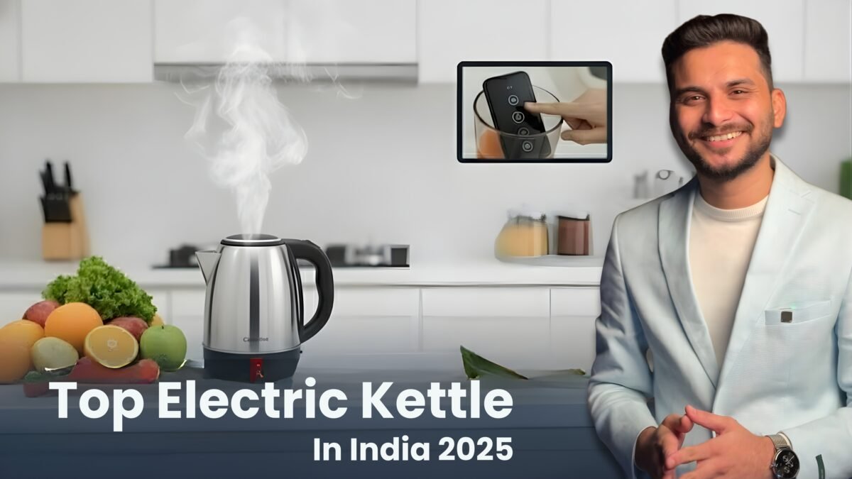 A modern, sleek stainless steel electric kettle with visible steam rising from its spout, positioned on a clean white kitchen counter. A man (Sourabh) in a light blue or white blazer smiles and gestures towards the kettle. An inset image shows a hand interacting with a smartphone displaying an app for controlling the kettle. The title "Top Electric Kettle In India 2025" is displayed at the bottom, against a blurred background of a contemporary kitchen.